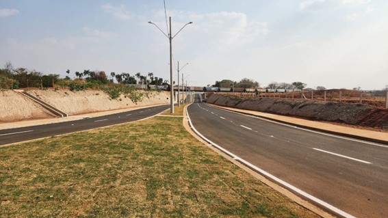 Uma estrada em primeiro plano. Ao fundo, um trem passando.