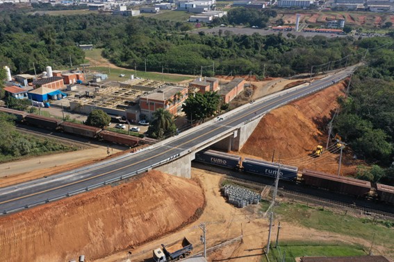 Imagem aérea da obra do viaduto. Trem da Rumo passa abaixo do viaduto.