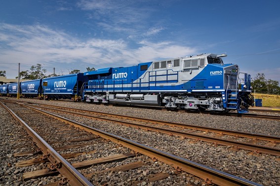 Locomotiva azul e cinza da Rumo puxando demais vagões. 